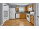 A well-lit kitchen showcasing wood floors, wooden cabinets, and white appliances at 1220 Skipping Rock Sw Ln, Grayson, GA 30017