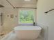Modern bathroom showcasing a soaking tub, walk-in shower, and scenic views from the window at 2478 Roseberry Ln, Grayson, GA 30017
