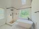 Modern bathroom showcasing a soaking tub, walk-in shower, and scenic views from the window at 2478 Roseberry Ln, Grayson, GA 30017