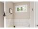 This bathroom features a white bathtub with a window and marble tile at 2484 Mcafee Rd, Decatur, GA 30032