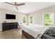 This bedroom features a dresser with a TV, a ceiling fan, and two windows at 2484 Mcafee Rd, Decatur, GA 30032