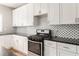Well-equipped kitchen features white cabinets, stainless steel oven, and elegant black and white backsplash at 2484 Mcafee Rd, Decatur, GA 30032