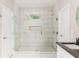 A glass shower featuring marble tile, a shower head, and two white doors at 2484 Mcafee Rd, Decatur, GA 30032