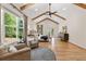 Bright main bedroom featuring hardwood floors, exposed beams, ceiling fan, seating, and a view of the backyard at 2553 Creekwood Ter, Decatur, GA 30030