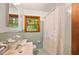 Bathroom with a window, white tile, a white sink, and shower with a patterned shower curtain at 470 Hunnicutt Se Rd, Mableton, GA 30126