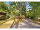 View of a landscaped front yard with driveway leading to a house surrounded by mature trees and foliage at 470 Hunnicutt Se Rd, Mableton, GA 30126