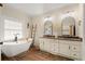 Bright bathroom featuring double sinks, granite countertop, soaking tub, wood floors, and decorative ladder at 6250 Bannerhorn Run, Alpharetta, GA 30005
