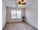 Cozy bedroom with neutral carpet and a ceiling fan is well-lit by a window at 7750 Carnegie Dr, Fairburn, GA 30213