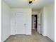 A simple bedroom with light carpet features a closet and entry to other rooms at 7750 Carnegie Dr, Fairburn, GA 30213