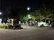 Night view of the community entrance with manicured landscaping and a clock tower in the background at 7750 Carnegie Dr, Fairburn, GA 30213