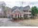 A brick two-story home featuring a double balcony, with a paved driveway and well-maintained landscaping and traditional style at 2930 Aquitania Ln, Cumming, GA 30040
