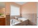Bright bathroom featuring a soaking tub with tile surround, perfect for relaxation and natural light at 60 Heritage Keep, Covington, GA 30016