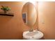 Stylish half-bathroom boasts a pedestal sink, an oval mirror, and a decorative plant on a glass shelf at 60 Heritage Keep, Covington, GA 30016