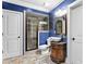A blue bathroom with a dark shower, vessel sink and two doors at 1985 Chapel Estates Ln, Dacula, GA 30019