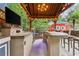 Outdoor kitchen boasts stainless steel grill, TV, speakers, and seating under covered patio at 1985 Chapel Estates Ln, Dacula, GA 30019