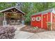 Inviting outdoor kitchen and shed features a covered bar with chairs and lights surrounded by lush landscaping at 1985 Chapel Estates Ln, Dacula, GA 30019