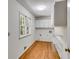 A well-lit laundry room featuring hardwood floors, storage cabinets and a window at 3573 Turtle Cove Se Ct, Marietta, GA 30067