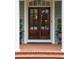 Close-up of a dark wood front door framed by white columns and surrounded by greenery in decorative pots at 492 Conway Manor Nw Dr, Atlanta, GA 30327