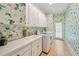 Charming laundry room with floral wallpaper, white cabinets, a utility sink and modern washer and dryer at 492 Conway Manor Nw Dr, Atlanta, GA 30327