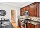 A well-lit kitchen with dark cabinets, stainless steel appliances, mosaic tile backsplash and an island with sink at 1620 Diplomat Dr, Cumming, GA 30041