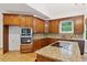 Kitchen featuring wooden cabinets, granite countertops, island with cooktop, and stainless steel appliances at 2305 Lochinver Sw Ln, Conyers, GA 30094