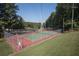 Well-maintained fenced tennis court featuring a green and red playing surface, surrounded by mature trees at 7098 Stonington Dr, Atlanta, GA 30328