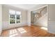 Sunlit living room with hardwood floors, large windows, and view to open staircase at 1459 Hickory Branch Nw Trl, Kennesaw, GA 30152