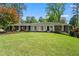 Charming single-story home featuring a well-manicured lawn, mature trees, and classic brick accents at 10 Wyndham Dr, Sandy Springs, GA 30328