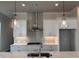 Bright kitchen features stainless appliances, white cabinets, quartz countertops and pendant lighting at 146 Birch Tree Way, Cumming, GA 30040