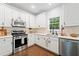 Bright kitchen features white cabinets, stainless steel appliances, and hardwood floors at 160 Wentworth Dr, Canton, GA 30114