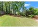 Large backyard features expansive green lawn, mature trees, and tiered landscaping at 1900 Chattahoochee Run Dr, Suwanee, GA 30024