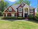 Beautiful two-story red brick home featuring manicured lawn, black shutters, and an arched entry at 1900 Chattahoochee Run Dr, Suwanee, GA 30024