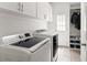 Bright laundry room with white cabinets, front load washer and dryer, tile floors, and storage at 1900 Chattahoochee Run Dr, Suwanee, GA 30024