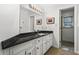 Bathroom featuring a single vanity with black countertop, white cabinets and a large mirror with modern lighting at 4794 Dalhousie Ne Pl, Marietta, GA 30068