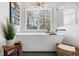 Bright neutral bathroom with modern soaking tub, large windows, and a view of greenery at 7390 Canter Run, Cumming, GA 30040