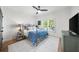 Bright bedroom showcasing a bed with a blue comforter, a ceiling fan, and a window with plantation shutters at 7390 Canter Run, Cumming, GA 30040
