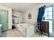 Bright bathroom featuring a large tiled tub, storage shelves, and natural light from a window at 3157 Brooks Dr, Snellville, GA 30078