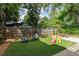 Fenced backyard with seating area, artificial turf, play equipment, and stone patio with dining at 342 5Th Ne St, Atlanta, GA 30308