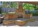 Outdoor stone fireplace with wood storage, accent lighting, and a grill area for cooking at 3590 Fricks Rd, Marietta, GA 30062
