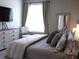 This bedroom features neutral decor, soft textures, a dresser with a TV and a bright window at 3630 Deaton Trl, Buford, GA 30519