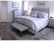 Main bedroom featuring a gray upholstered bed with a decorative bench and wood-look floors at 3630 Deaton Trl, Buford, GA 30519