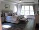 Bright main bedroom with tray ceiling, a large window, and a gray upholstered bed and bench at 3630 Deaton Trl, Buford, GA 30519