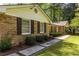 Close-up of a brick home with dark shutters, manicured bushes, and a concrete walkway at 1602 Shamrock Se Trl, Smyrna, GA 30080