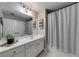 Well-lit bathroom featuring a white vanity, a large mirror, and a shower with a gray curtain at 1738 Honey Tree Pl, Hoschton, GA 30548