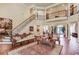 Open living room featuring a grand staircase, hardwood floors, ornate columns and detailed wood furniture at 5004 Gunnison Trce, Suwanee, GA 30024