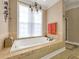 Bright bathroom featuring a soaking tub with tile surround, chandelier, and decorative wall art at 200 Suffolk Way, Mcdonough, GA 30252