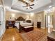 Main bedroom featuring a tray ceiling, hardwood floors, and a plush bed with a dark wood frame at 200 Suffolk Way, Mcdonough, GA 30252