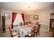 Cozy dining room featuring a chandelier, window with red curtains, and six person dining table at 1030 E Lakehaven Way, Mcdonough, GA 30253