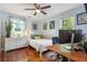 Bright bedroom with hardwood floors, ceiling fan, large windows, and a white dresser and bed frame at 502 Allgood Ne Rd, Marietta, GA 30060