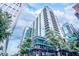 Modern high-rise building with glass balconies, surrounded by greenery and street signs under a blue sky at 923 Peachtree Ne St # 1625, Atlanta, GA 30309